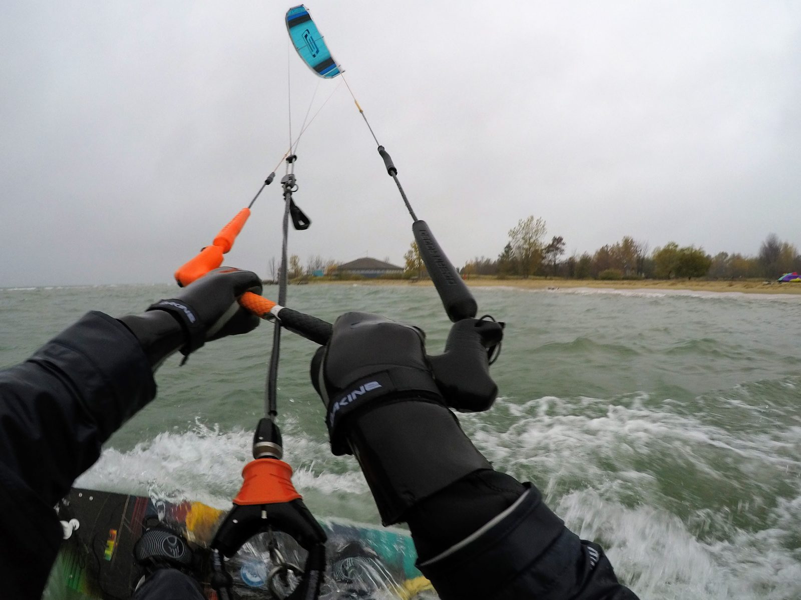 Kiteboarder's point of view riding along the Lake Huron shore at Tawas Point, hands on the bar, low sandy beach and autumn trees in the background